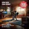 A woman is exercising on a stationary bike in a living room with a TV on. Produktbild-Vorschau