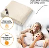 A woman and a child are lying in bed, smiling and looking happy, with a folded electric blanket in the background. Produktbild-Vorschau