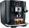 A black JURA coffee machine with two glasses of espresso in front of it. Produktbild-Vorschau