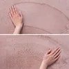 A close-up of a hand touching a soft, pink rug. Produktbild-Vorschau