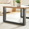 A close-up view of a coffee table with a wooden top and black metal legs, placed on a light-colored rug. Voir les images du produit