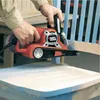 A person is using a belt sander to sand a chair. Anteprima dell’immagine prodotto