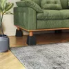 A green corduroy sofa with black furniture risers under its legs, next to a potted plant and a rug. Produktbild-Vorschau