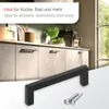 A kitchen or bathroom cabinet with black handles and screws, with a coffee machine and plants in the background. Produktbild-Vorschau