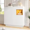 A white cabinet with a wooden accent niche, displayed in a well-lit room with a window and a plant. Produktbild-Vorschau