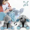 Grauer Plüsch-Elefant mit hellblauen Ohren und Füßen, in zwei Posen gezeigt, mit einem spielenden Kind im Hintergrund Voir les images du produit