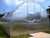 A large, transparent greenhouse structure with a silver frame, set up outdoors on grass and paving stones. Podgląd zdjęcia produktu