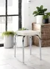 A stool is placed in a room with plants and a wooden chest. Produktbild-Vorschau