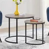Two round nesting coffee tables with gray wood-look tops and black metal frames are shown on a patterned rug. Produktbild-Vorschau