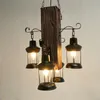 A rustic-style chandelier with a wooden beam and four lantern-shaped lights. Produktbild-Vorschau