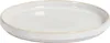 A close-up, studio shot of a single, cream-colored ceramic plate with a ribbed edge, set against a plain white background. Náhľad obrázku produktu