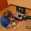 A young child is playing with a toy tool bench on a wooden floor. Voir les images du produit