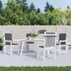 A white outdoor dining set with chairs and a table on a patio, with a wooden fence and trees in the background. Náhľad obrázku produktu