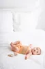 A baby lying on a white bed. Produktbild-Vorschau