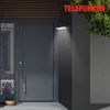 An outdoor wall light illuminates a modern dark gray door and a potted plant with lavender. Produktbild-Vorschau