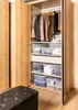 An open wardrobe with clothes hanging and storage boxes on shelves. Anteprima dell’immagine prodotto