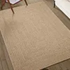 A braided jute-look rug is placed on a wooden floor, partially visible under a wooden chair and next to a white sofa. Produktbild-Vorschau
