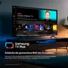 A Samsung TV displaying the Samsung TV Plus interface, placed on a media console with ambient lighting. Produktbild-Vorschau