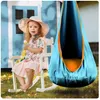 A young girl sits in a rocking chair next to a hanging cocoon swing. Voir les images du produit