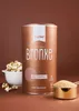 A bronze colored canister of Xucker Bronxe Erythrit sweetener is shown in the center, with a bowl of popcorn to the left and a measuring cup filled with the sweetener to the right. Produktbild-Vorschau
