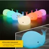 Multiple whale-shaped night lights in various colors, with a close-up of one light in the foreground. Produktbild-Vorschau