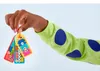 A child's hand holds a set of colorful LEGO DOTS bag tags. Produktbild-Vorschau