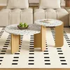 A set of two round coffee tables with terrazzo-style tops and wooden legs, placed on a rug in a living room setting. Voir les images du produit