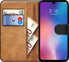 A book-style phone case with a phone inserted, showing cards and banknotes inside. Produktbild-Vorschau