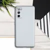 A silver smartphone case is shown from the back on a wooden surface, with some greenery and a notebook in the background. Produktbild-Vorschau