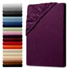 A stack of folded sheets in various colors is shown on the left, and a single aubergine-colored fitted sheet is displayed on the right, angled to show its texture and elastic edge. Produktbild-Vorschau