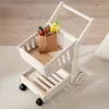 A wooden toy shopping cart filled with toy groceries sits on a light-colored rug. Produktbild-Vorschau