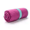 A rolled-up pink towel with a teal strap, isolated on a white background. Produktbild-Vorschau