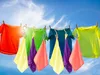 Colorful t-shirts and cloths are hanging on a clothesline against a bright blue sky with some clouds. Anteprima dell’immagine prodotto