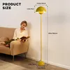 A woman is reading a book on a sofa next to a yellow floor lamp with product dimensions indicated. Produktbild-Vorschau