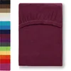 A folded burgundy fitted sheet is shown against a white background, with a strip of other colored fitted sheets visible on the left side. Produktbild-Vorschau