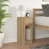 A bedside table with a drawer and an open shelf, next to a bed and a plant. Podgląd zdjęcia produktu