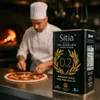 A chef is preparing a pizza in a kitchen with a wood-fired oven in the background, and a large can of olive oil is prominently displayed in the foreground. Produktbild-Vorschau