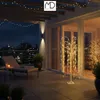 A balcony at night with a decorative illuminated willow tree and string lights. Podgląd zdjęcia produktu