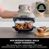 A hand holding a Ninja Crispi Powerpod over a glass dish filled with food, with spices in wooden bowls nearby. Anteprima dell’immagine prodotto