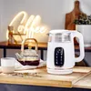A white electric kettle and a glass teapot are on a wooden surface, with a neon 'Coffee' sign in the background. Produktbild-Vorschau