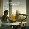 A man is working at a desk with a monitor mounted on an arm. Produktbild-Vorschau