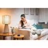 A woman is relaxing on a sofa, interacting with a smart speaker. Anteprima dell’immagine prodotto
