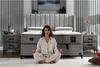 A woman meditating in front of a bed in a bedroom. Produktbild-Vorschau