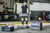 A man is holding a tool box in a workshop setting. Náhled obrázku produktu