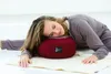 A woman is lying on a yoga mat with her head resting on a red meditation cushion. Produktbild-Vorschau