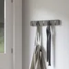A modern coat rack with hooks mounted on a wall, with a bag and scarves hanging from it. Náhľad obrázku produktu