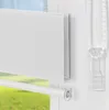 A close-up view of a white roller blind with a beaded pull cord and a clear plastic cord holder, set against a blurred background of green grass and blue sky. Produktbild-Vorschau