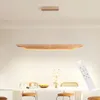 A modern wooden pendant light hangs over a dining table. Voir les images du produit