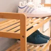 A close-up view of a two-tiered bamboo shoe rack with shoes on both shelves. Podgląd zdjęcia produktu