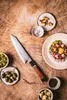 A knife and ingredients for a meal are arranged on a wooden surface. Podgląd zdjęcia produktu